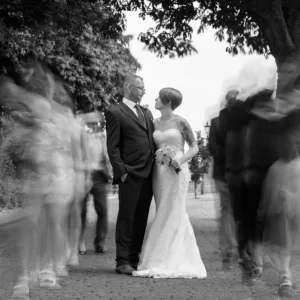 North Devon Photographer - Robb Webb Award-winning black and white wedding photograph of a bride and groom standing still while guests move around them in motion blur