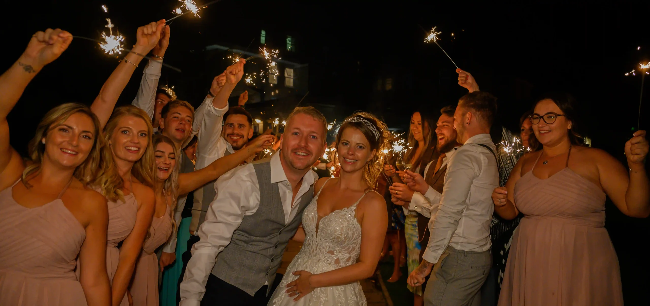 Bride and groom celebrating with guests holding sparklers at a wedding in North Devon, photographed by Robb Webb